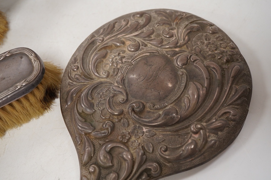 Four assorted early 20th century repousse silver mounted dressing table items to include a hand mirror, two hair brushes and a clothes brush(a.f.).
